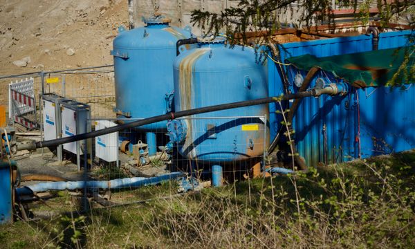 Water Filtration & Borehole Systems โ Outdoor industrial water filtration plant with large blue tanks under sunlight.