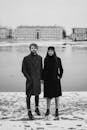 一对时髦的夫妇穿着优雅的冬装，站在冰冻的湖边