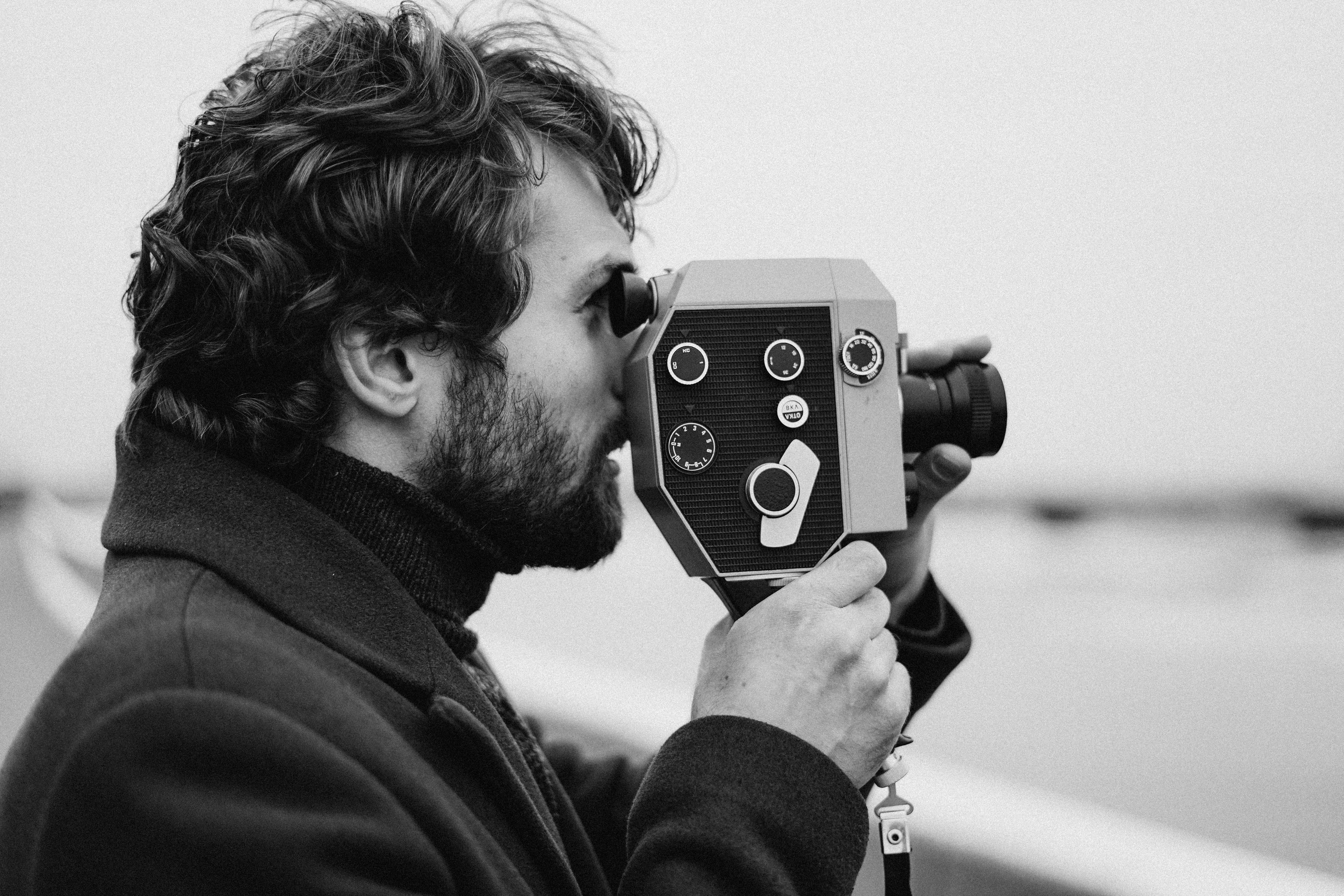 man in black coat holding camera