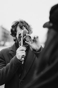 Black and white photo of a man using a vintage camera outdoors.
