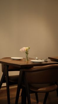 A clean, minimalist dining setup featuring a small vase with delicate flowers.