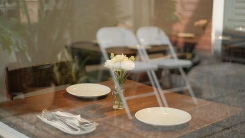 Free View of a rustic cafe table through a window, adorned with flowers and set for a meal. Stock Photo