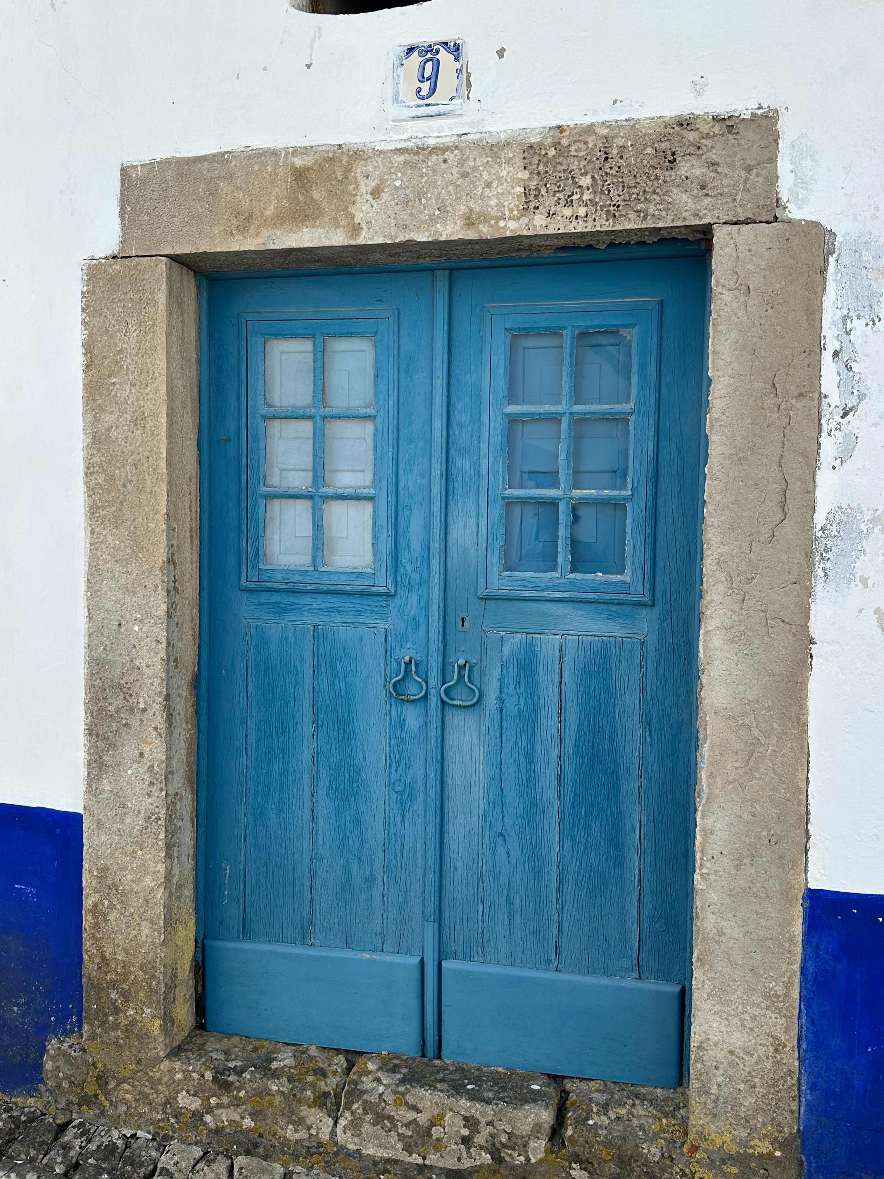 Charming blue door with rustic stone frame in Óbidos, Portugal.