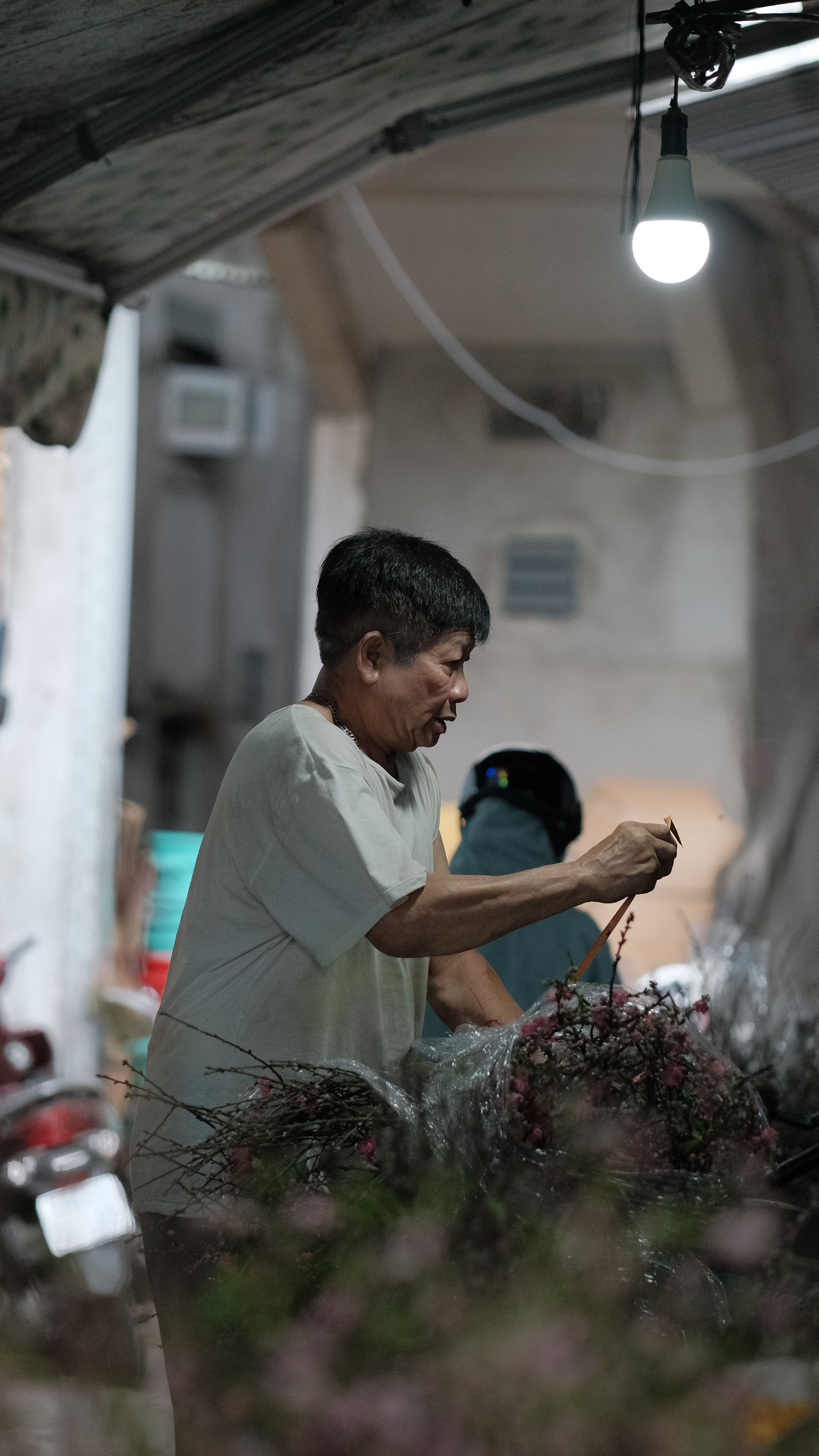 A man arranges flowers under a dim light, showcasing concentration and craft.