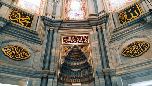 Free A detailed view of a historic mosque's interior featuring stunning Arabic calligraphy and intricate architectural design. Stock Photo