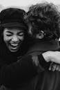 一张单色图像中，一对快乐的夫妇在户外拥抱欢笑，洋溢着幸福