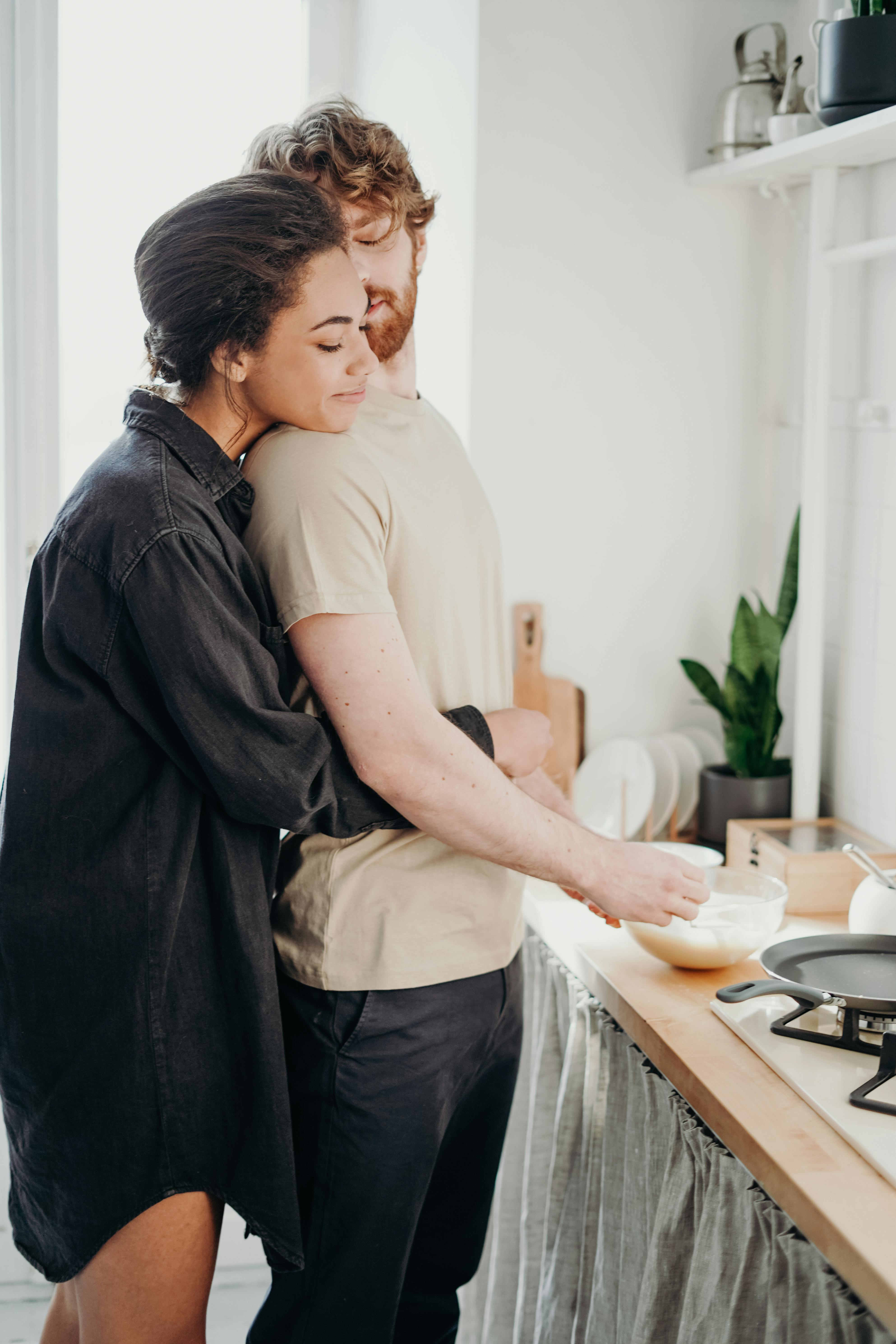 Woman hugging her man in the kitchen. | Photo: Pexels