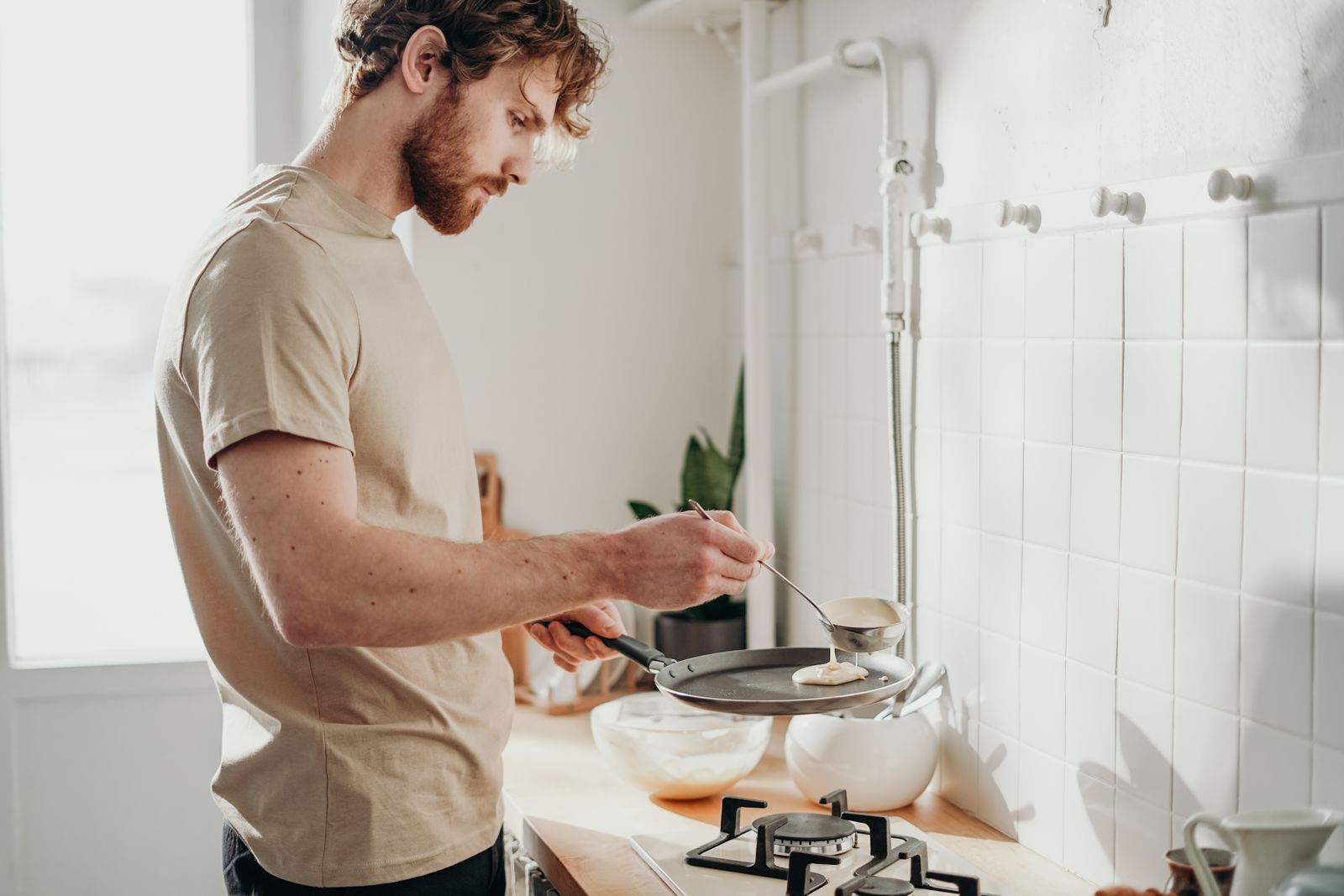 Young man preparing a simple breakfast in a sunlit home kitchen