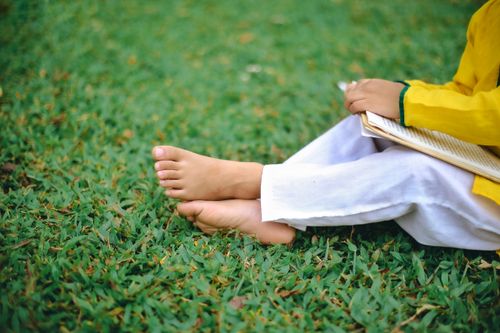 Free A child sitting on grass enjoying a book, promoting relaxation and literacy. Stock Photo