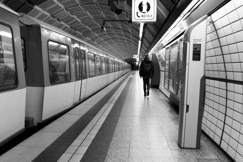 Free Empty subway station with lone traveler and train in black and white. Stock Photo