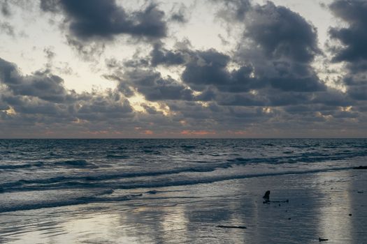 Calm waves and dramatic clouds create a picturesque sunset at Andaman Islands.