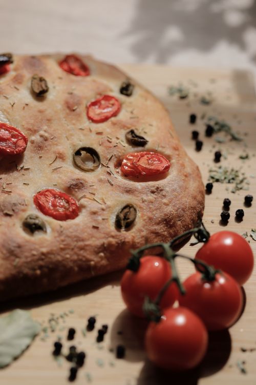 Free Rustic focaccia bread topped with cherry tomatoes and olives, captured in natural light. Stock Photo