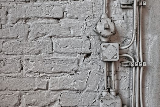 A vintage brick wall featuring aged electrical wires and boxes, showcasing industrial design.