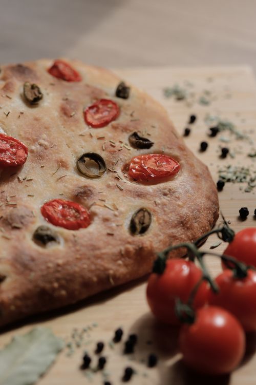 Free Freshly baked focaccia topped with tomatoes and olives, perfect for home cooking enthusiasts. Stock Photo