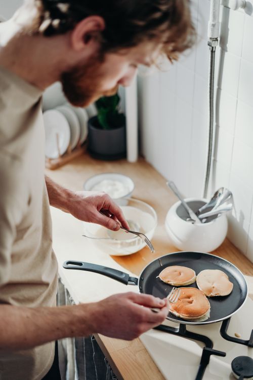Free A man prepares delicious pancakes in a warm, cozy kitchen, capturing a morning routine. Stock Photo