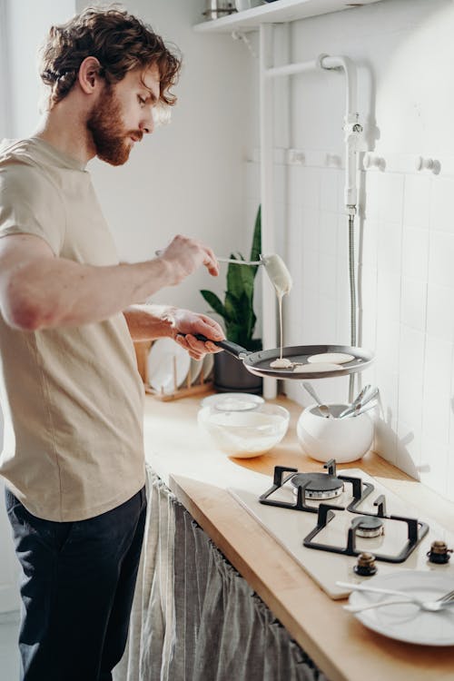 Mann, Der Bratpfanne Hält Und Milch Gießt