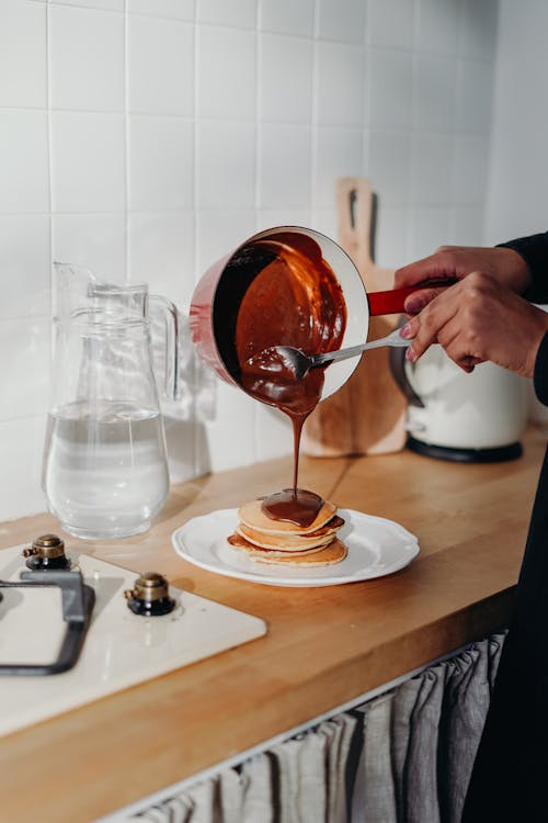Person Pouring Chocolate on Pancake