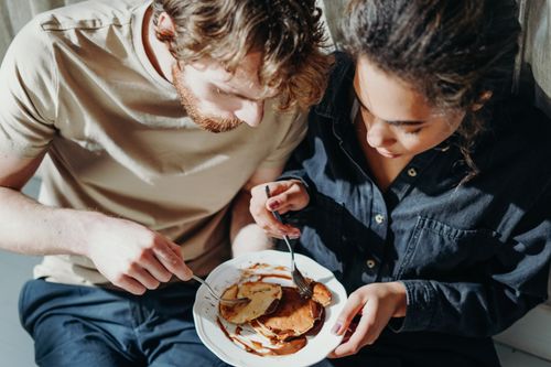 Free A couple shares a delightful pancake breakfast indoors under morning sunlight. Stock Photo