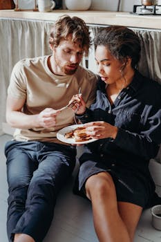一对年轻夫妇在室内分享煎饼，享受温馨舒适的早餐，展现了家庭的温暖与团结