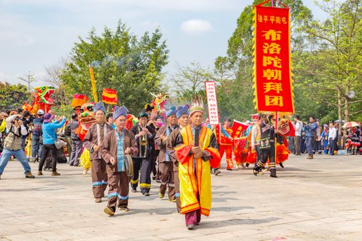 Vibrant parade in Guangxi, China featuring traditional costumes and cultural banners.