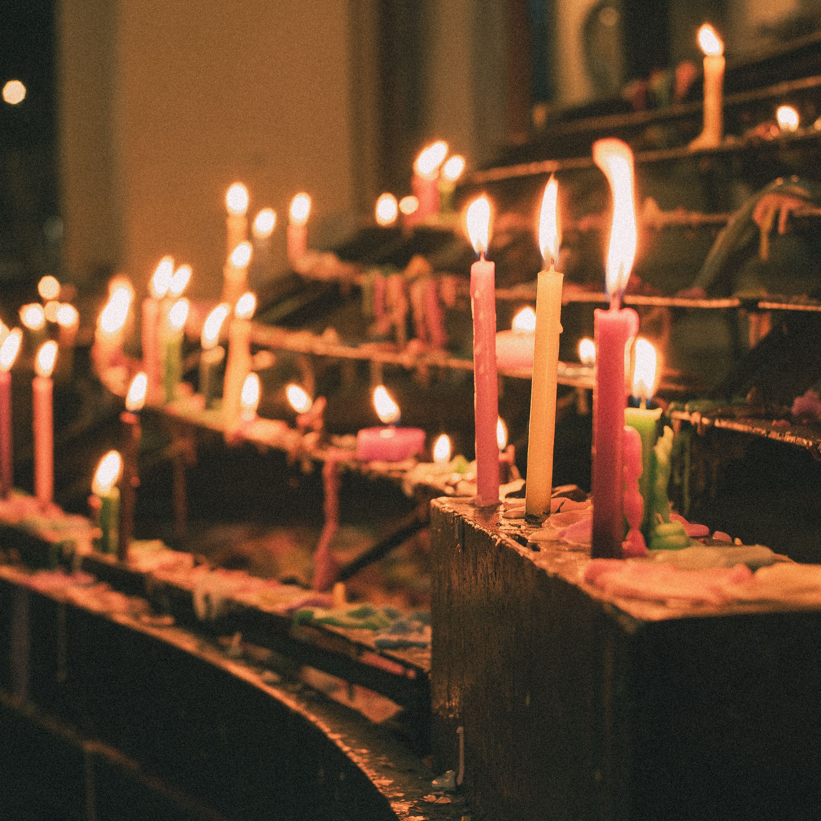 A serene candlelit scene with colorful candles in a dimly lit indoor setting, evoking warmth and tranquility.