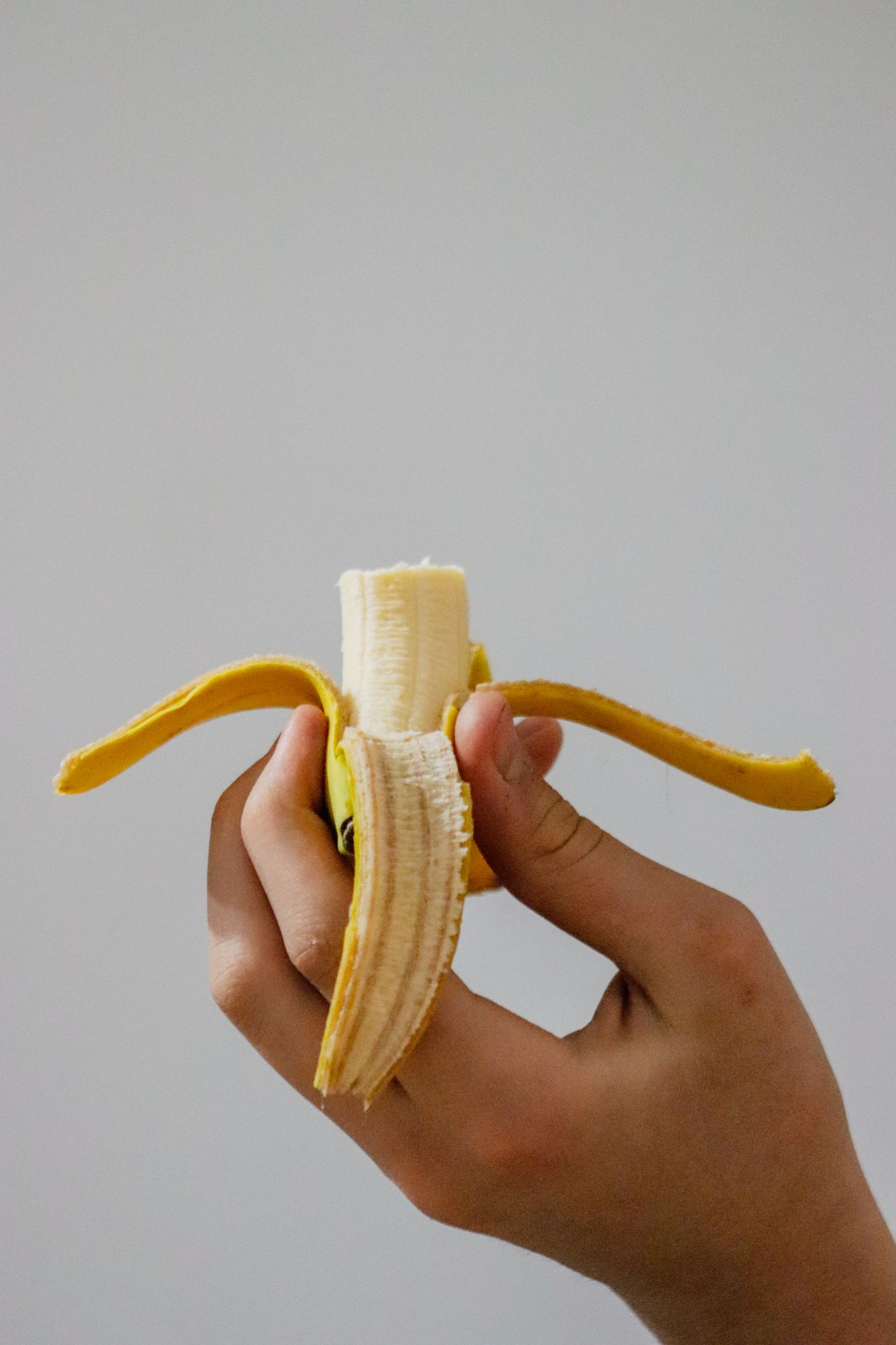 Tangan memegang pisang sebagai contoh camilan buah