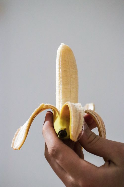 Free Close-up of a hand peeling a fresh banana, showcasing texture and color. Stock Photo