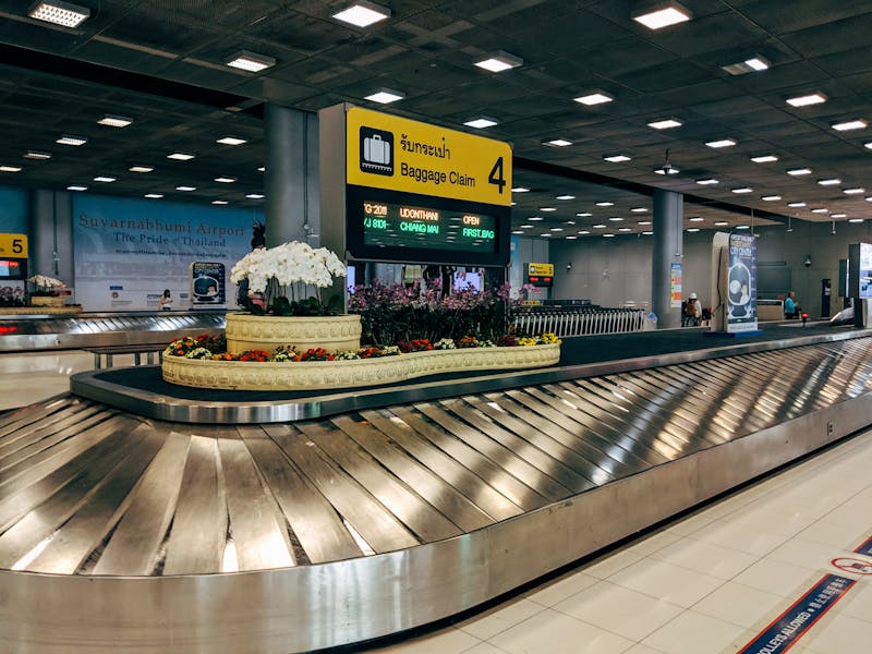 Modern baggage claim area at Suvarnabhumi Airport in Bangkok with luggage carousel and signage.