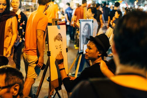 Man in a black t shirt and hat sketching