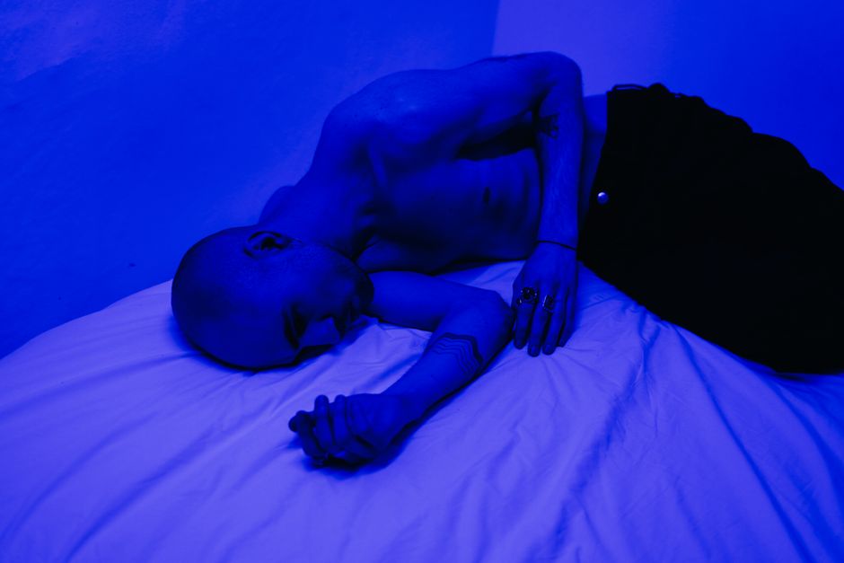 Man in a blue-lit room, expressing solitude and introspection.