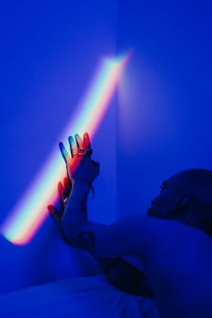 晚上，一个秃头的男人伸手触摸蓝色照明墙上的彩色彩虹灯