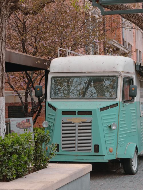 Free A vintage, mint-green food truck parked in an urban setting during springtime. Stock Photo