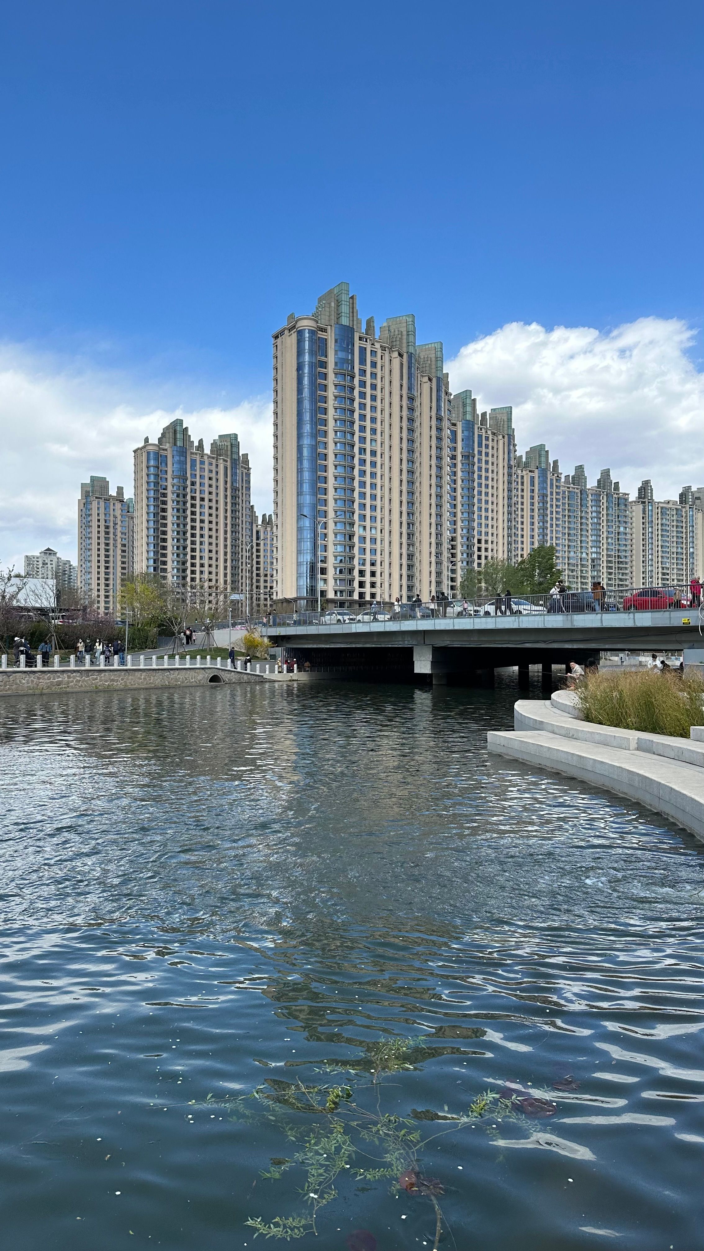 Modern skyscrapers reflecting in waterfront with clear blue sky in Beijing.
