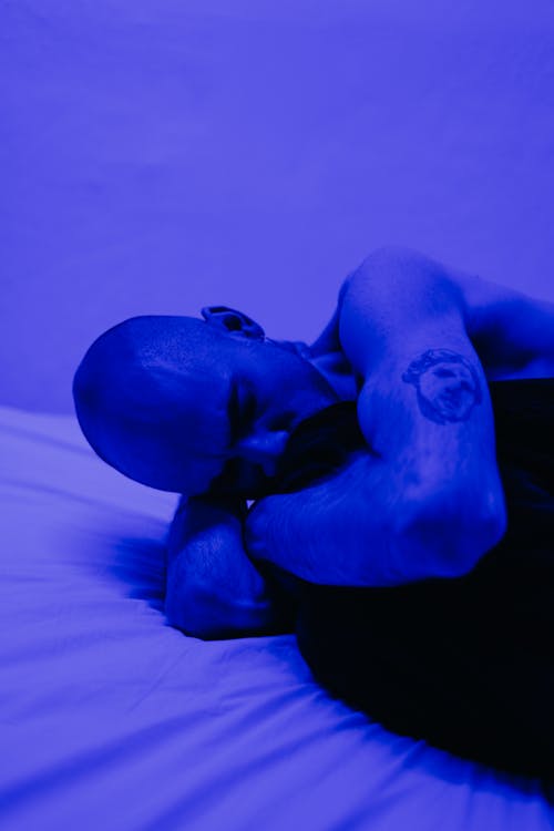 Shirtless man in blue lit room