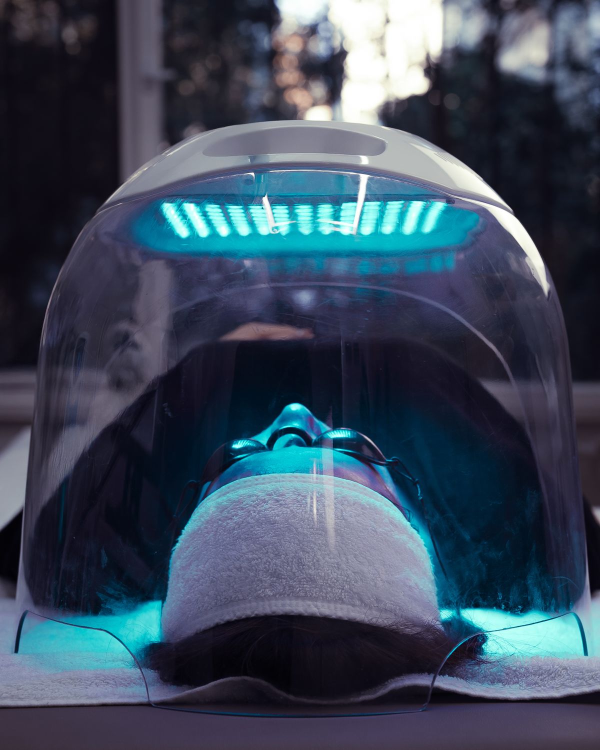 Client resting under an LED light therapy dome