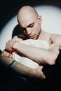 一个秃头、纹身的男人拥抱着石膏头像，表达情感
