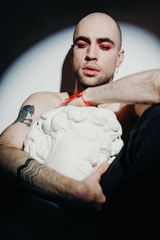 一名纹身男子手持雕塑头，戏剧性的灯光营造出强烈的情绪