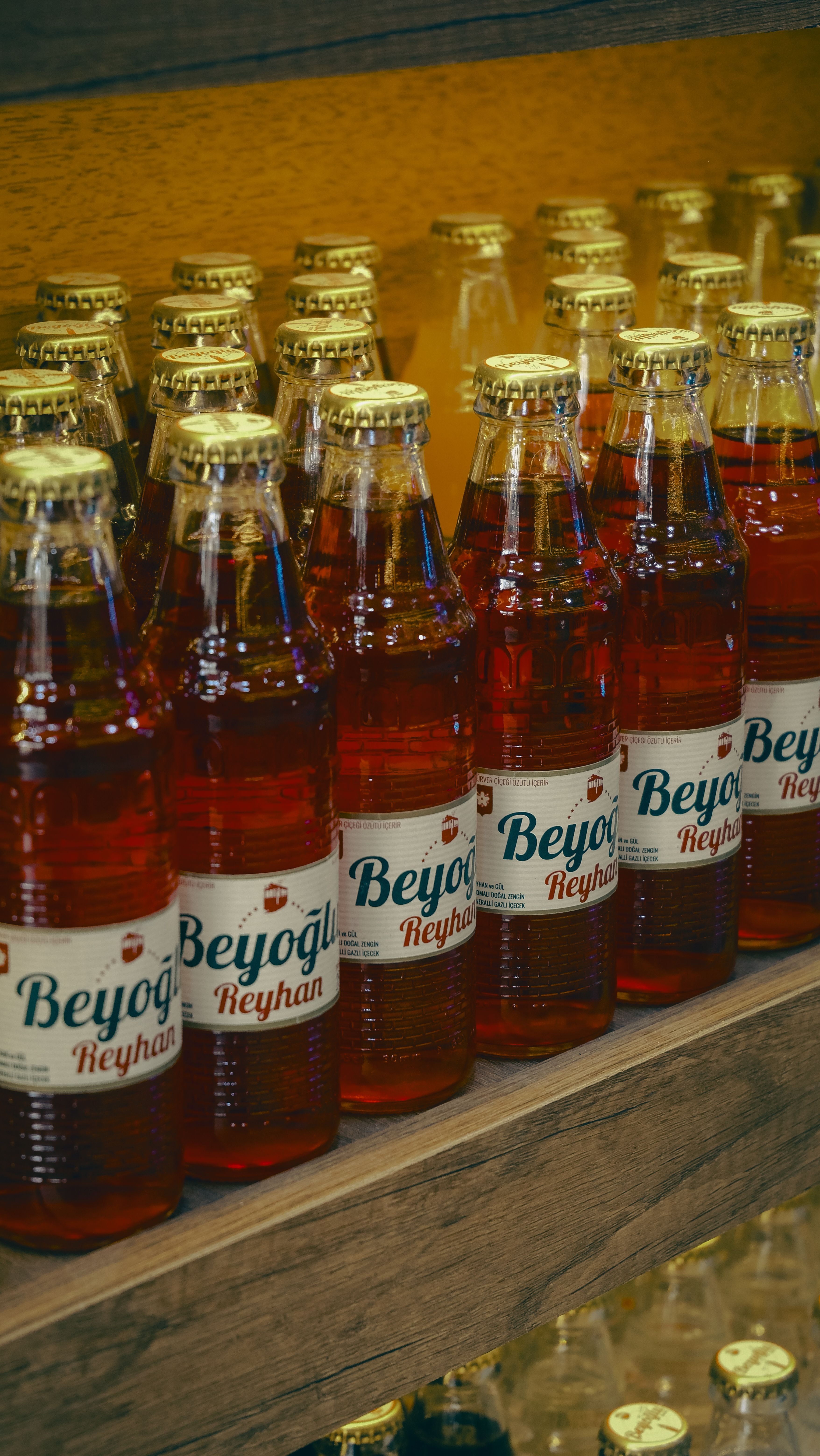 Rows of Beyoğlu soda bottles arranged on a shelf in a Turkish market.