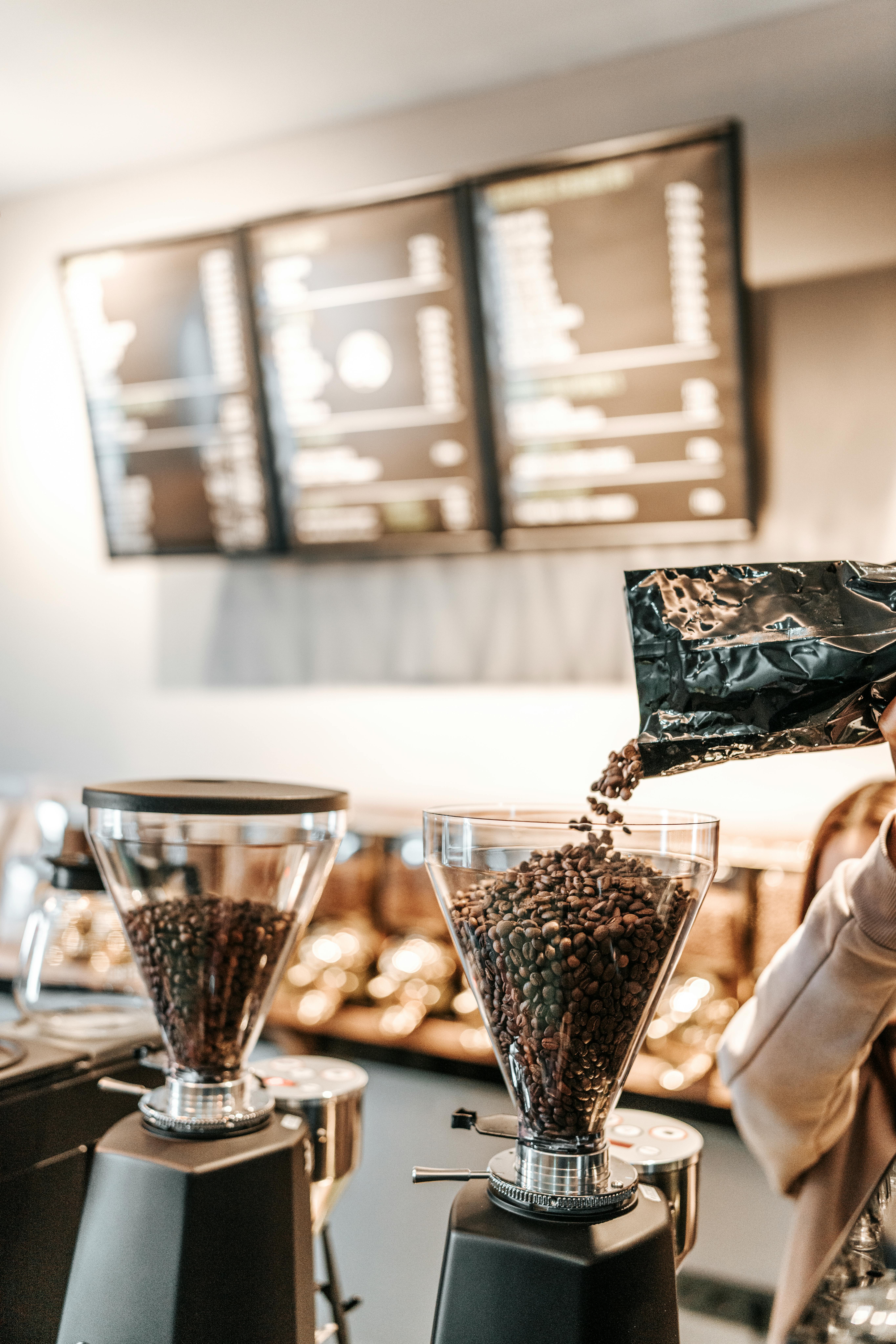 Coffee beans being poured into grinders at a cozy Istanbul café, with menu boards in the background.