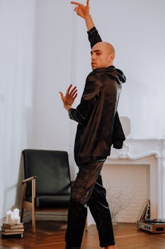 一名秃头男子身着黑衣，在现代风格的室内背景下摆出动态的舞蹈姿势