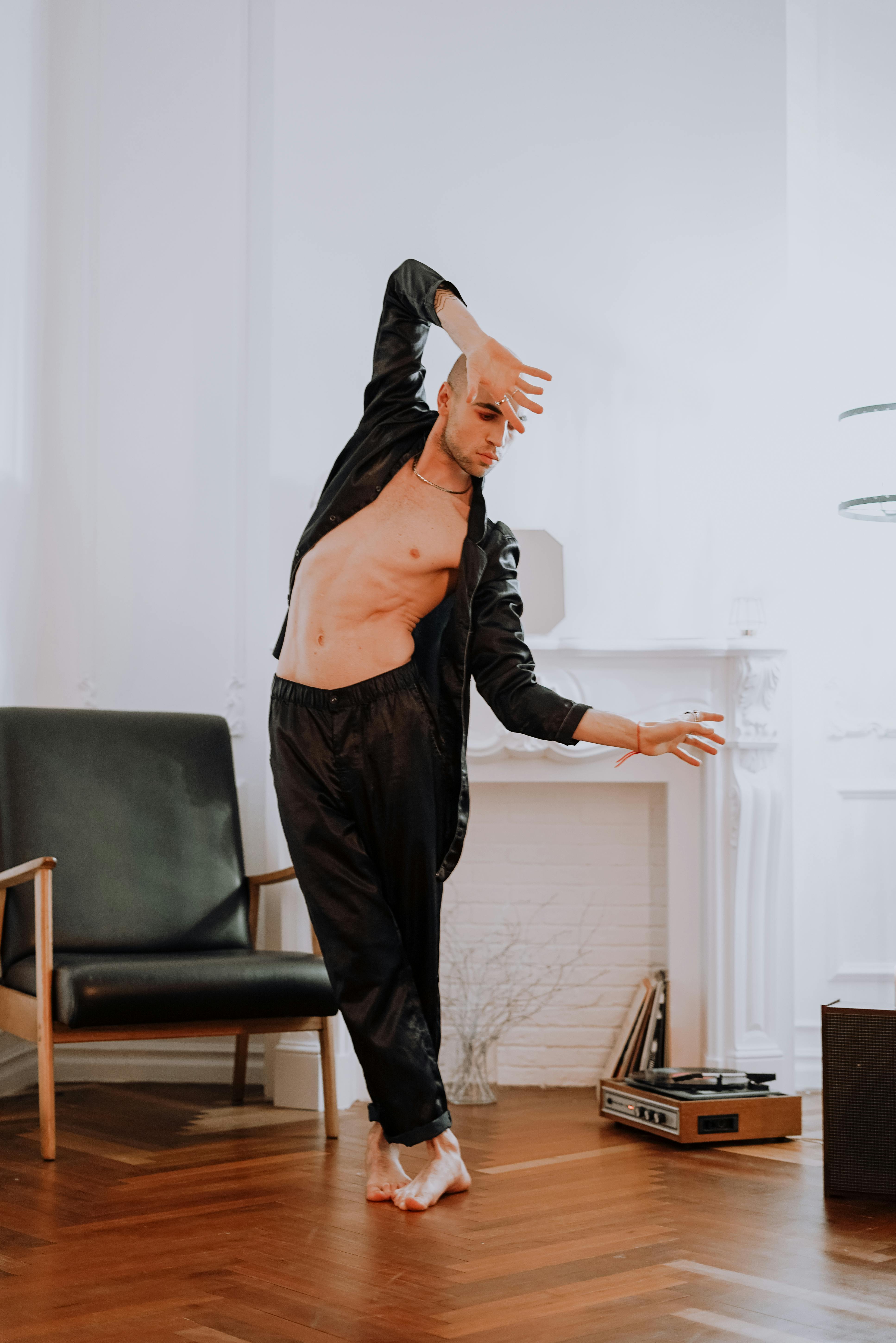 一位身着黑衣的男性舞者在优雅的室内环境中摆出姿势的艺术镜头