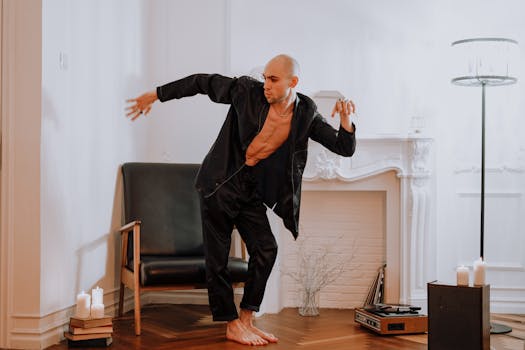 一名身着黑衣的秃头男子在室内，伴着蜡烛和复古氛围翩翩起舞