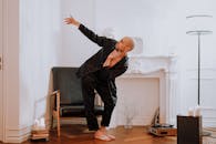 一位穿着黑色服装的秃头男人在装饰优雅的室内表演富有表现力的舞蹈