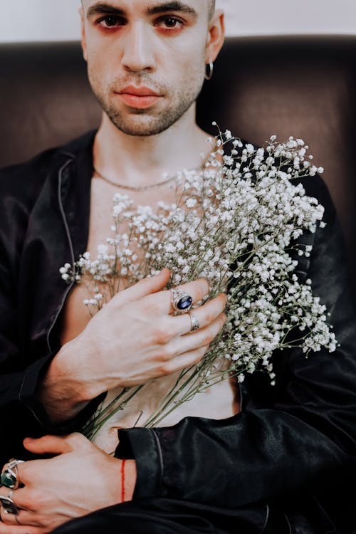 Man in Black Jacket Holding White Flowers