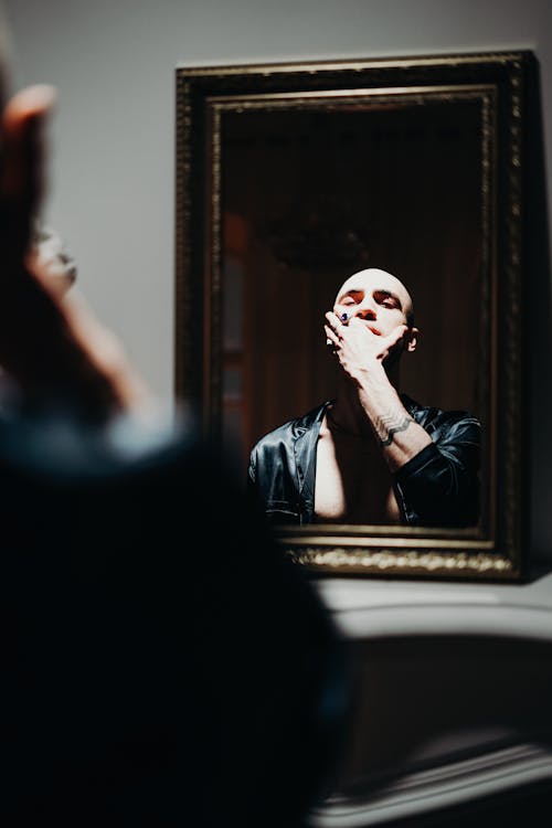 Free Man Looking at the Mirror  in Holding His Face Stock Photo