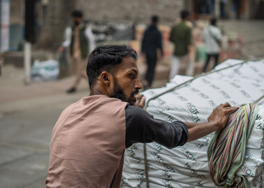 A dedicated worker pulls heavy packages on a cart down a bustling city street, evoking themes of hard work and industry.