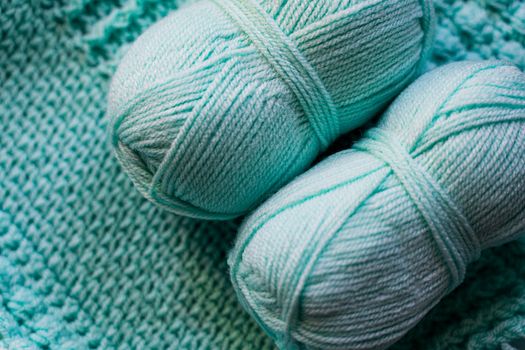 Detailed close-up of teal yarn balls resting on a vibrant knitted textile background.