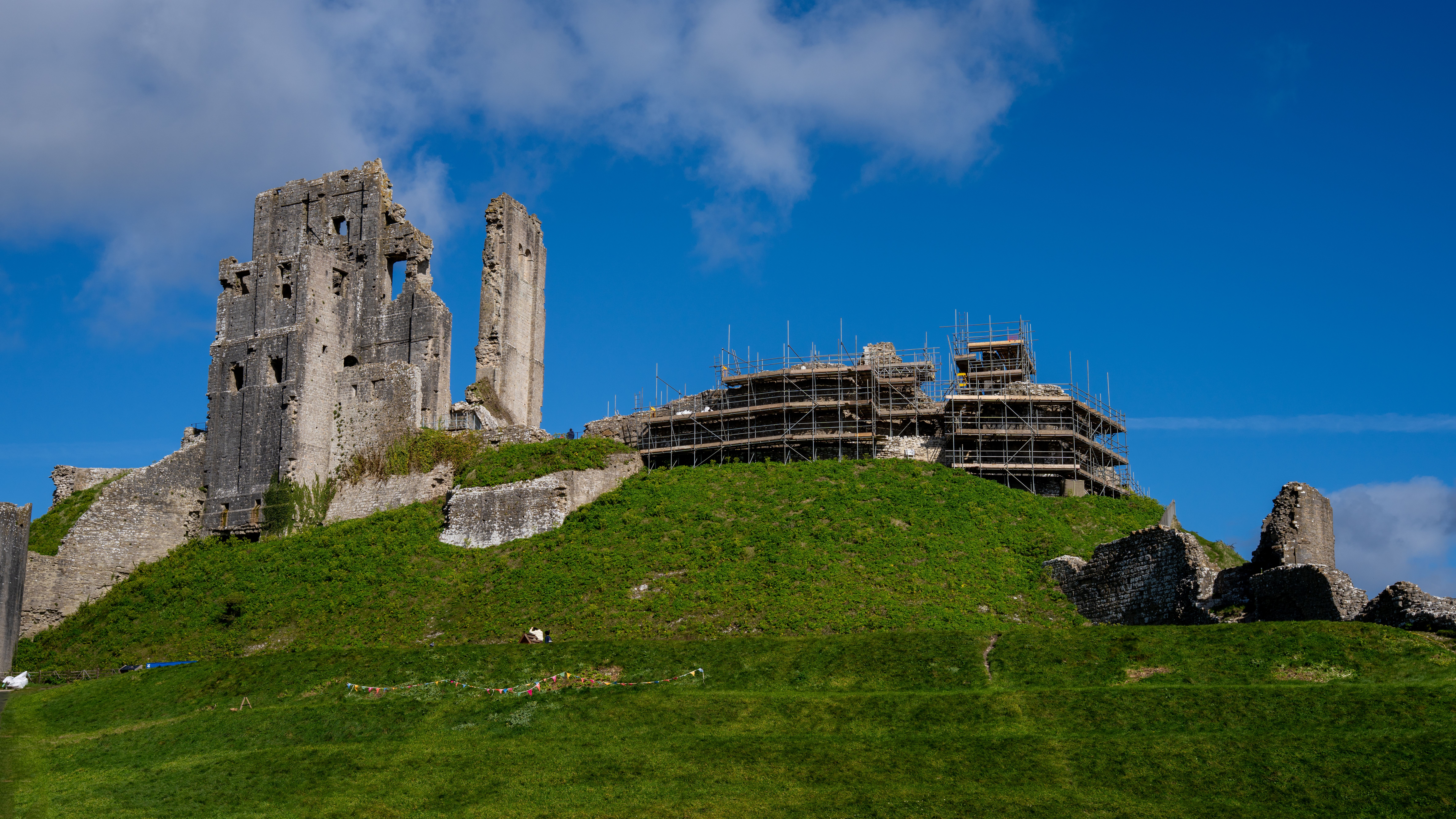 Explore the historic ruins of Corfe Castle set against a vibrant blue sky in England.