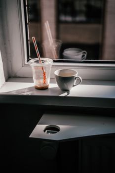 A warm, inviting scene showing coffee cups on a sunlit windowsill. Perfect for cozy coffee moments.