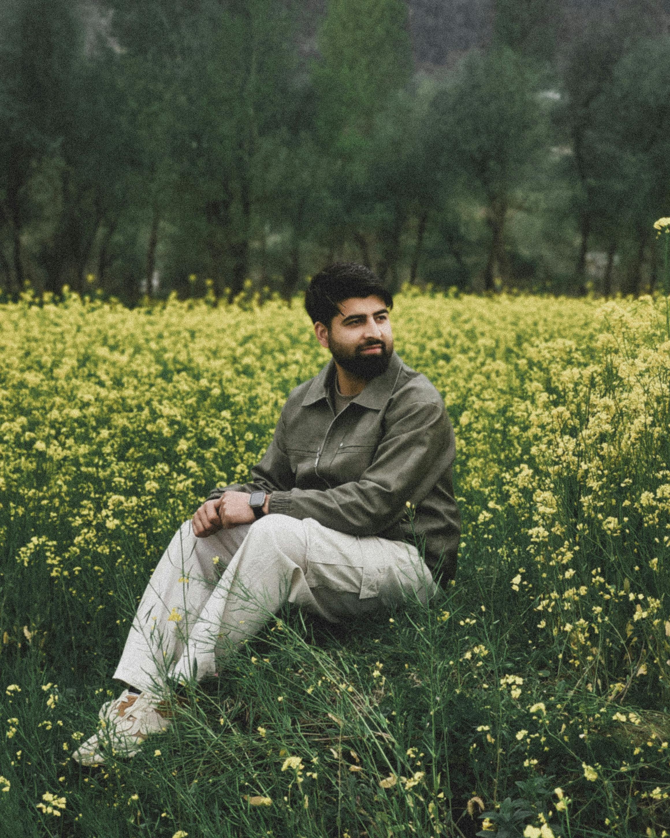 A man sits pensively in a vibrant yellow mustard field during springtime.